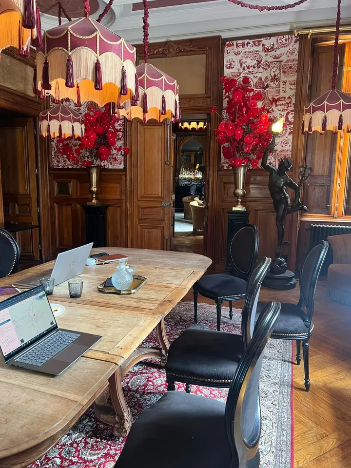 Le salon du château aménagé pour la formation : grande table en bois, ordinateurs portables, boiseries et abat-jour à franges