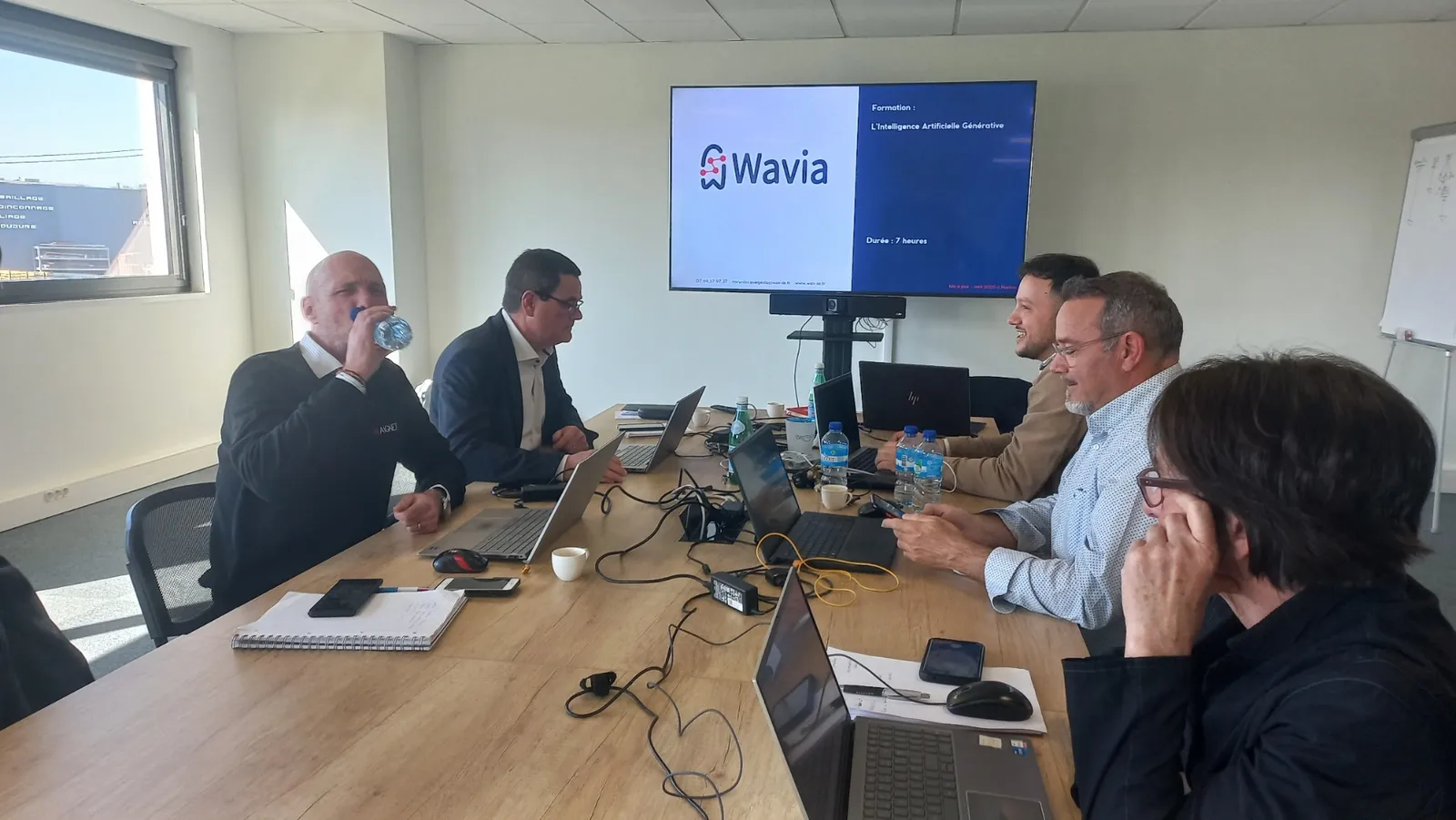 Session de formation IA Wavia en salle de réunion, participants devant leurs ordinateurs