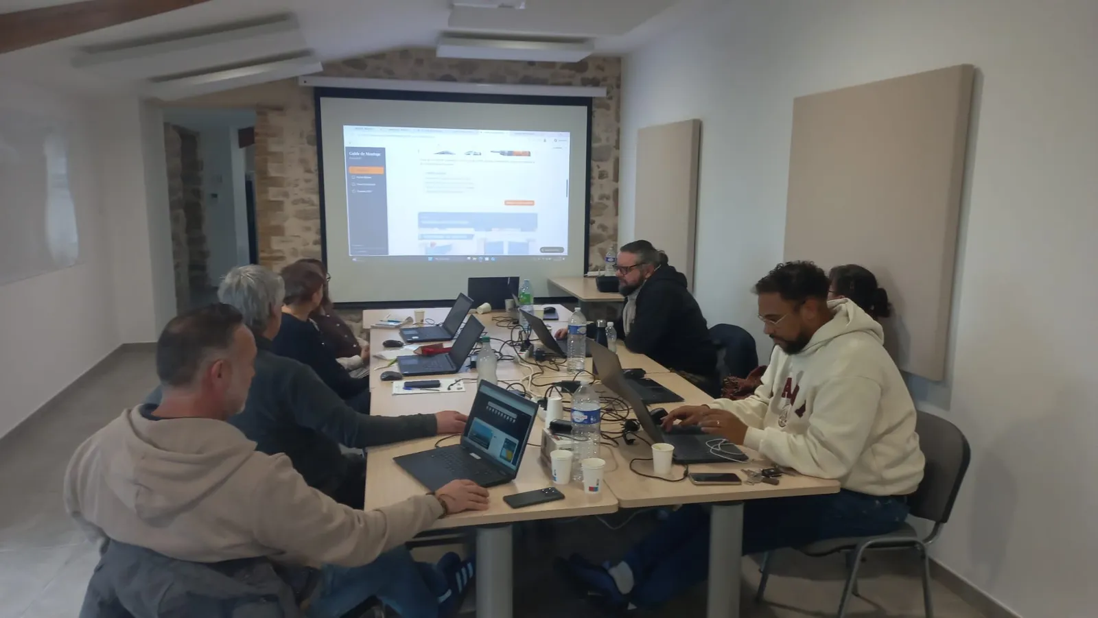 Session de formation IA Wavia en entreprise : participants autour de la table, ordinateurs ouverts